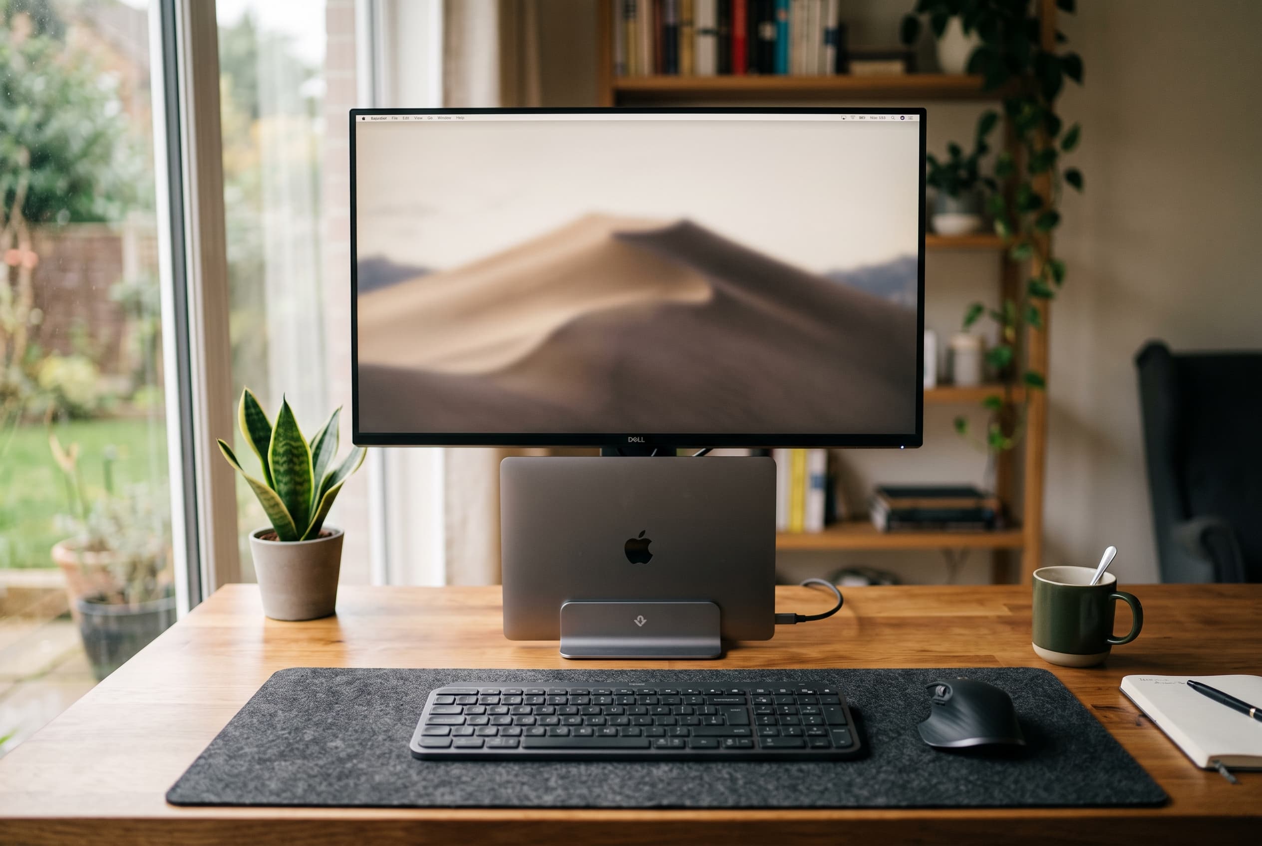 Home office desk with centered external monitor, closed laptop dock, keyboard, and mouse arranged ergonomically